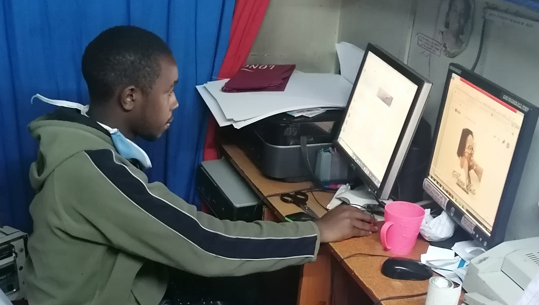 Josee at his Cyber Cafe serving client photo credit by: Ronald Mukanga